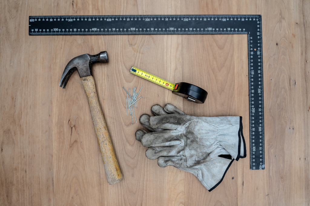 hammer, tape measure, gloves, and square on floor